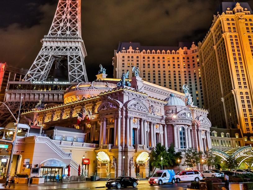 imagem noturna vista de baixo da fachada do hotel paris e da imponente torre eiffel réplica